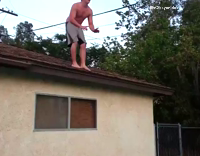 Shirtless guy grey shorts belly flop roof