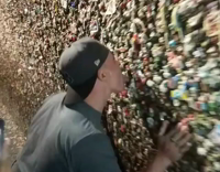 Guy in hat walks down and licks gum wall