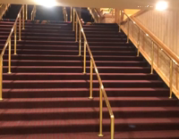 Blue Shirt Tries Slide Down Gold Railing on Red Stairs and Falls
