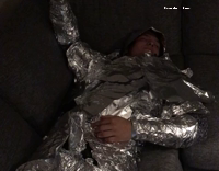 Guy on couch wrapped in foil to look like a knight
