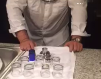Guy In White Shirt Tries To Pull Kitchen Towel From Under Glasses. Breaks All Of Them
