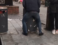 Puffy black jacket guy squatting trashcan